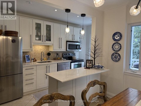 A kitchen with a refrigerator, microwave, and oven.
