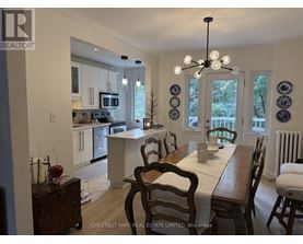 A dining room with a table set for two and a kitchen in the background.