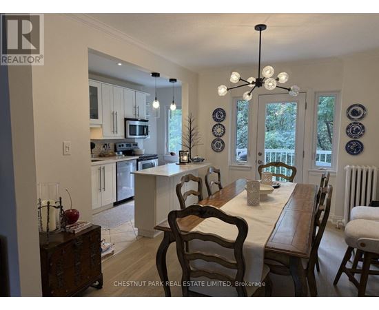 A dining room with a table set for two and a kitchen in the background.