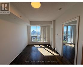 A well-lit, empty room with a view of the city through the windows.