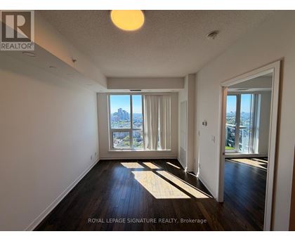 A well-lit, empty room with a view of the city through the windows.