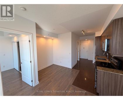 A well-lit, spacious room with wooden flooring and white walls.