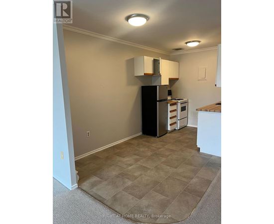 A kitchen area with a black refrigerator and a microwave.