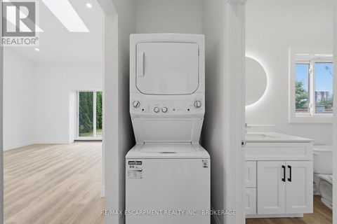 A white washing machine in a room with wooden flooring.