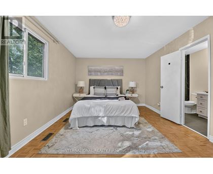 A bedroom with a large bed and a rug on the floor.