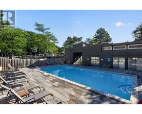 A swimming pool surrounded by lounge chairs and trees.
