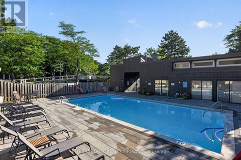 A swimming pool surrounded by lounge chairs and trees.