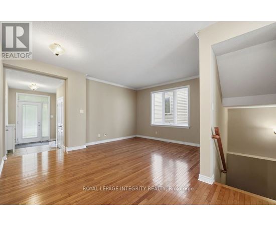A spacious room with wooden floors and a large window with white blinds.