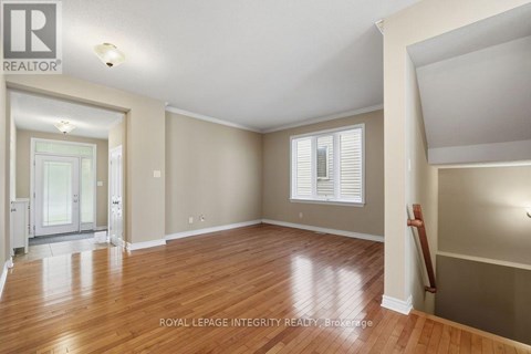A spacious room with wooden floors and a large window with white blinds.