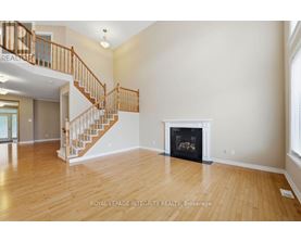 A spacious living room with a fireplace and a staircase.
