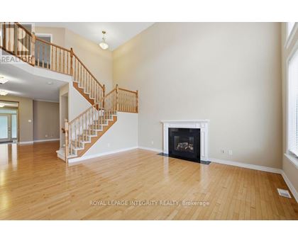A spacious living room with a fireplace and a staircase.