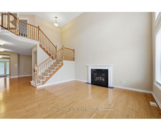 A spacious living room with a fireplace and a staircase.