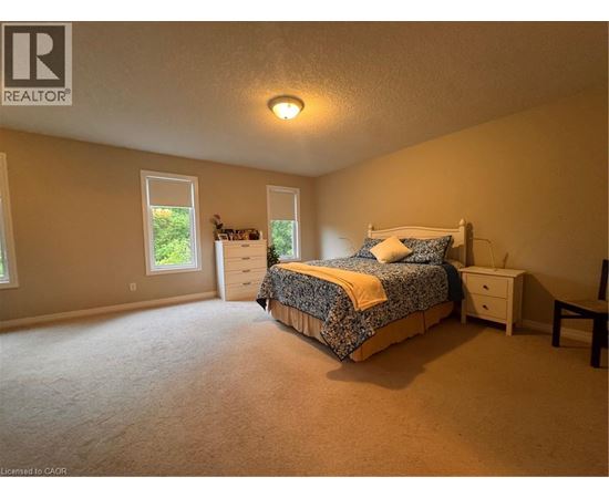 A bedroom with a bed, nightstand, and window.