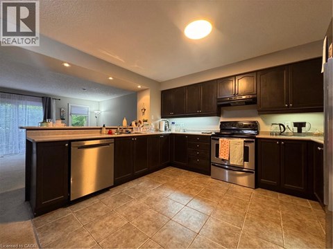 A kitchen with dark wood cabinets and a tile floor.