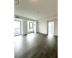 A spacious room with wooden flooring and large windows.