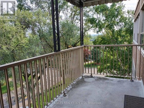 A balcony with a metal railing and a view of trees.