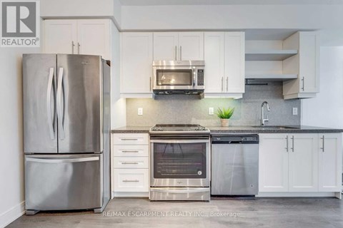 A modern kitchen with a stainless steel refrigerator and oven.