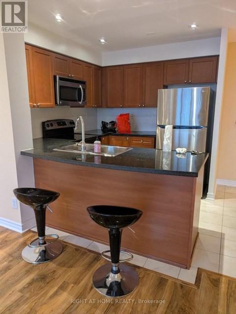 A kitchen with a black counter top and two black stools.