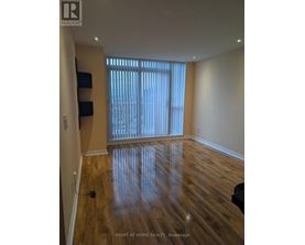A room with wooden flooring and a window with blinds.