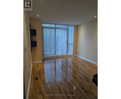 A room with wooden flooring and a window with blinds.
