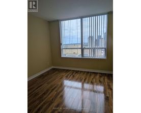 A room with wooden floors and a window overlooking a cityscape.