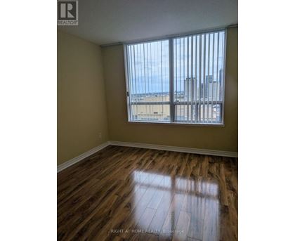 A room with wooden floors and a window overlooking a cityscape.