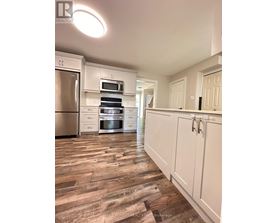 A kitchen with white cabinets and a wooden floor.