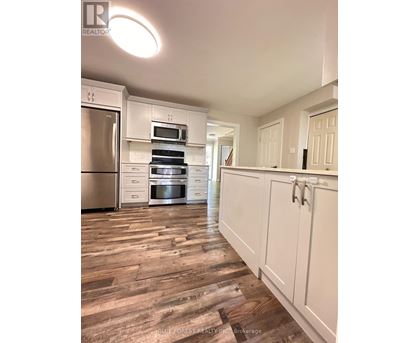 A kitchen with white cabinets and a wooden floor.