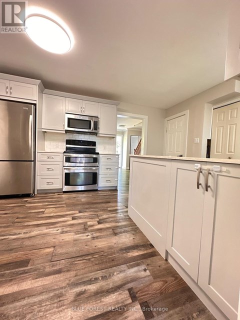A kitchen with white cabinets and a wooden floor.