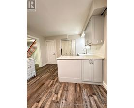 A kitchen with white cabinets and a wooden floor.