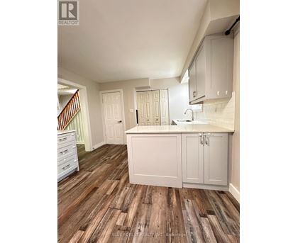 A kitchen with white cabinets and a wooden floor.