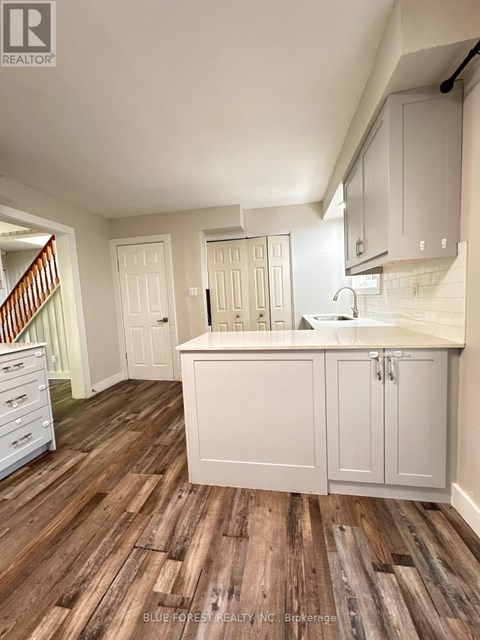 A kitchen with white cabinets and a wooden floor.