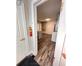 A hallway with a white door and a red fire extinguisher on the wall.