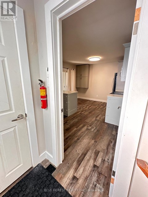 A hallway with a white door and a red fire extinguisher on the wall.