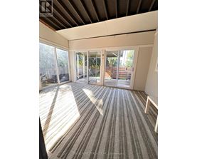 A sunny room with striped carpeting and sliding glass doors.