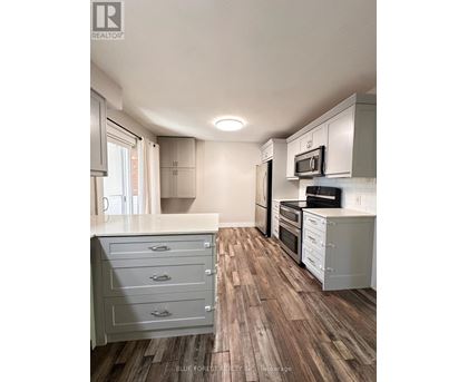 A kitchen with white cabinets and a wooden floor.