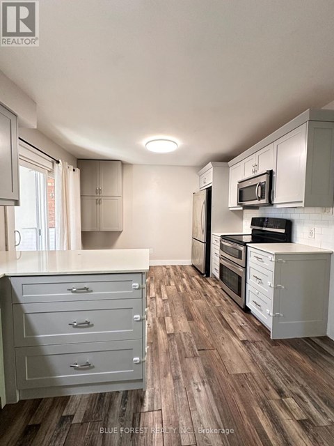 A kitchen with white cabinets and a wooden floor.