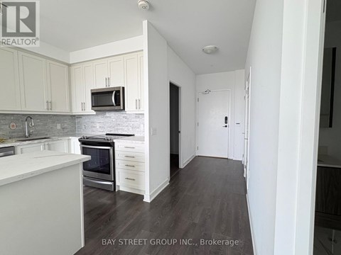 A kitchen with white cabinets and a grey backsplash.
