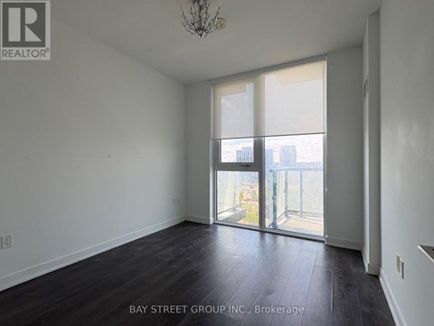 A room with a chandelier and a view of the city through the windows.