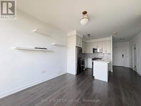 A spacious kitchen with white cabinets and a wooden ceiling light.