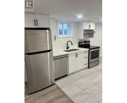 A modern kitchen with a stainless steel refrigerator and white cabinets.