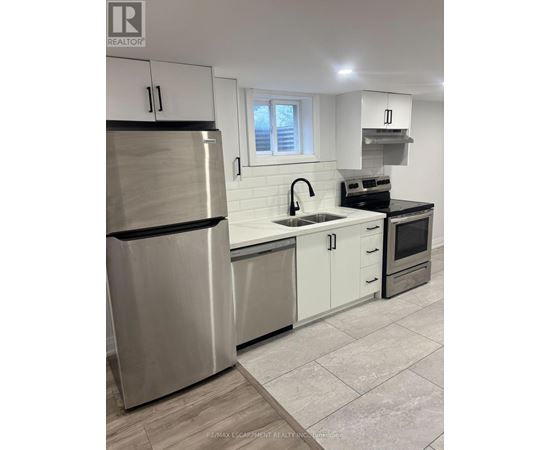 A modern kitchen with a stainless steel refrigerator and white cabinets.