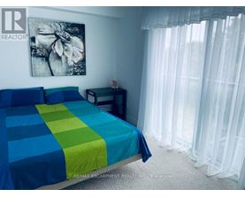A bedroom with a bed covered in a blue and green striped comforter.