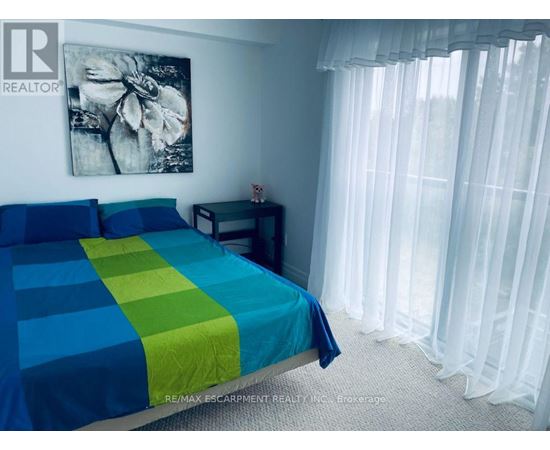 A bedroom with a bed covered in a blue and green striped comforter.