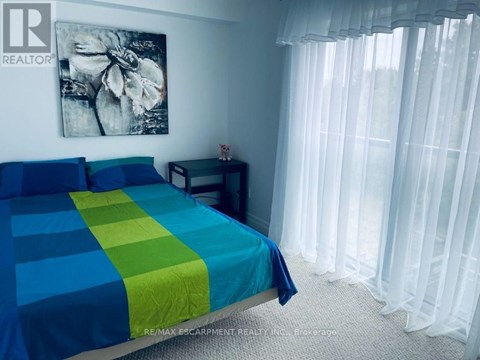 A bedroom with a bed covered in a blue and green striped comforter.