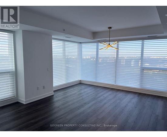 A room with a wooden floor and a large window with blinds.