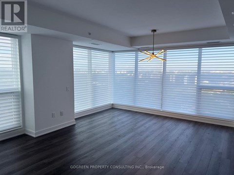 A room with a wooden floor and a large window with blinds.