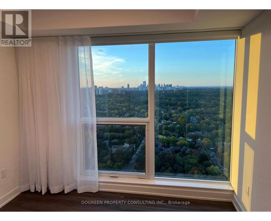 A room with a view of the city through a large window.