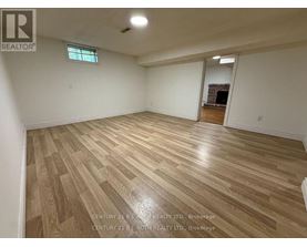 A spacious room with wooden flooring and a fireplace in the corner.