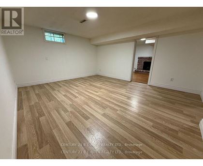 A spacious room with wooden flooring and a fireplace in the corner.